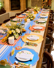 Summer table setting with a blue striped runner, colourful placemats and citrus napkins.
