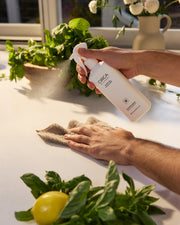 White Tea & Wild Mint Counter Spray being sprayed onto a kitchen counter beside a cleaning cloth.