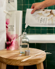 Oceanique diffuser refill being poured into a glass diffuser vessel.