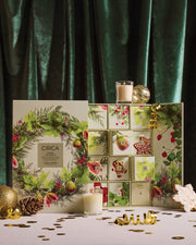 12 Days Advent Calendar styled open with candles, botanical gift boxes and gold Christmas decorations.
