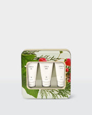 Three Christmas Hand Creams displayed through the window of a botanical gift tin.