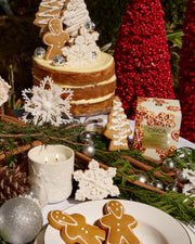 Gingerbread Cookies candle in its embossed ceramic vessel styled with gingerbread biscuits, cake and Christmas decorations.